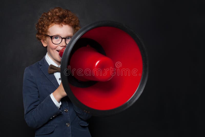 Αστείο κακό αγόρι παιδιών που μιλά μέσω ενός μεγάφωνου στο υπόβαθρο πινάκων Παιδί με κόκκινο megaphone