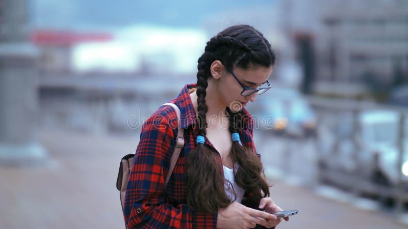 αστική ζωή : κορίτσι που στέκεται στο δρόμο της πόλης και στέλνει μηνύματα στο τηλέφωνο εν μέσω κυκλοφορίας