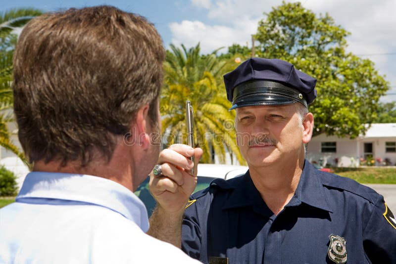 Police officer holding a pen and doing a field sobriety test on a motorist. Police officer holding a pen and doing a field sobriety test on a motorist.