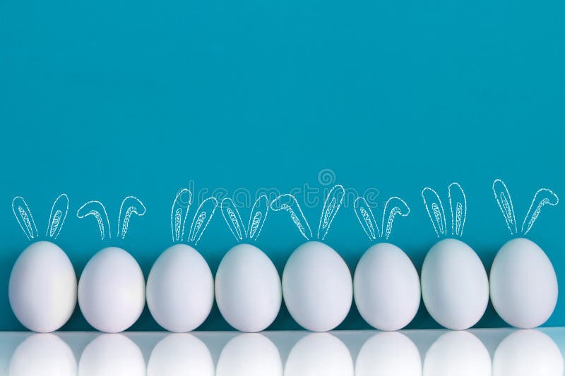 Αυγά Πάσχας που χρωματίζονται με τα αυτιά κουνελιών και ballooons στο μπλε υπόβαθρο