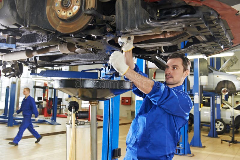 Car mechanic with spanner tighten car suspension detail of lifted automobile at repair service station. Car mechanic with spanner tighten car suspension detail of lifted automobile at repair service station