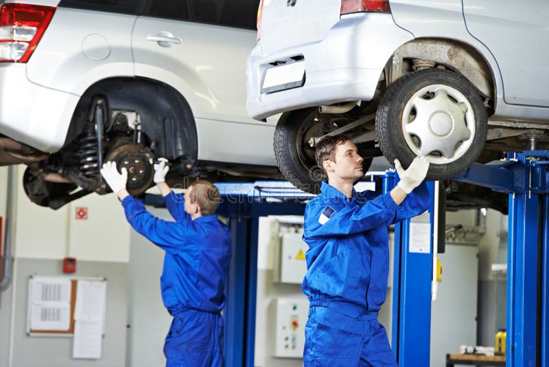 Car mechanic inspecting car wheel and suspension detail of lifted automobile at repair service station. Car mechanic inspecting car wheel and suspension detail of lifted automobile at repair service station