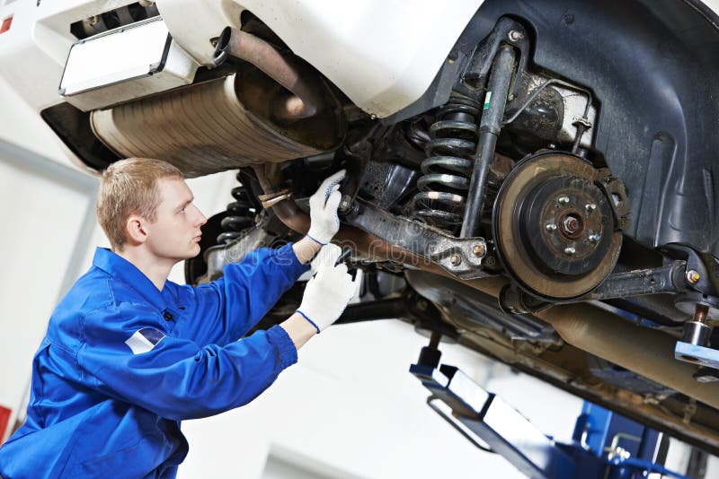 Car mechanic inspecting car wheel and suspension detail of lifted automobile at repair service station. Car mechanic inspecting car wheel and suspension detail of lifted automobile at repair service station