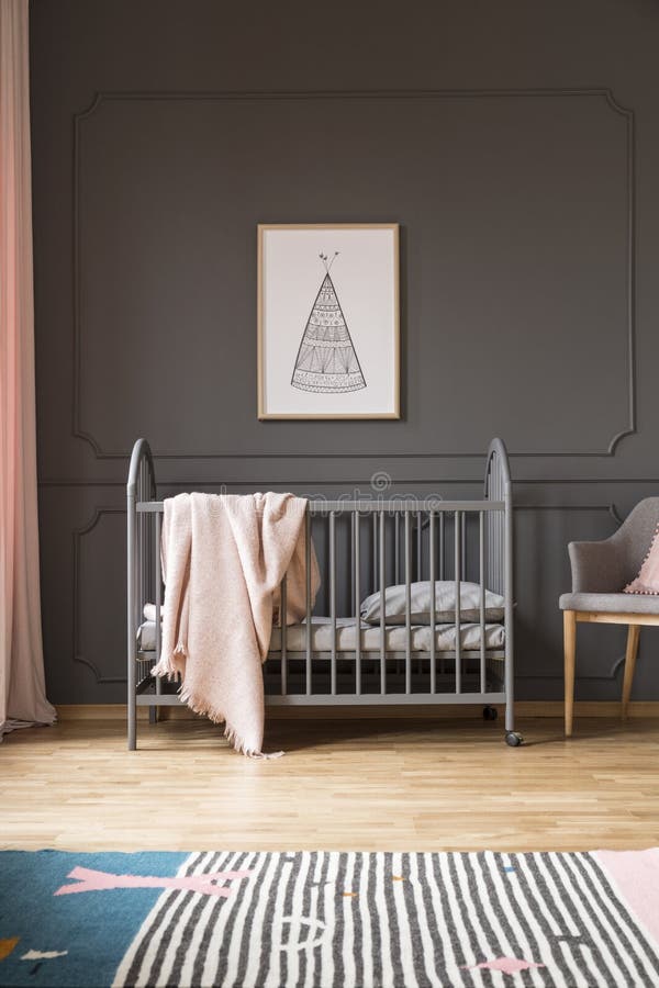 Poster on grey wall above bed with pink blanket in baby`s bedroom interior with carpet. Real photo concept. Poster on grey wall above bed with pink blanket in baby`s bedroom interior with carpet. Real photo concept