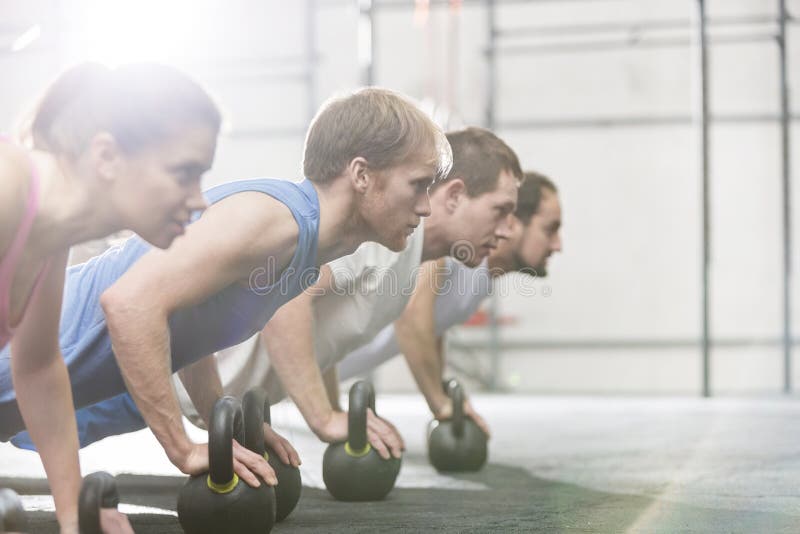 Αφιερωμένοι άνθρωποι που κάνουν pushups με τα kettlebells στη γυμναστική crossfit στοκ εικόνες με δικαίωμα ελεύθερης χρήσης Αφιερωμένοι άνθρωποι που κάνουν pushups με τα kettlebells στη γυμναστική crossfit στοκ εικόνες με δικαίωμα ελεύθερης χρήσης