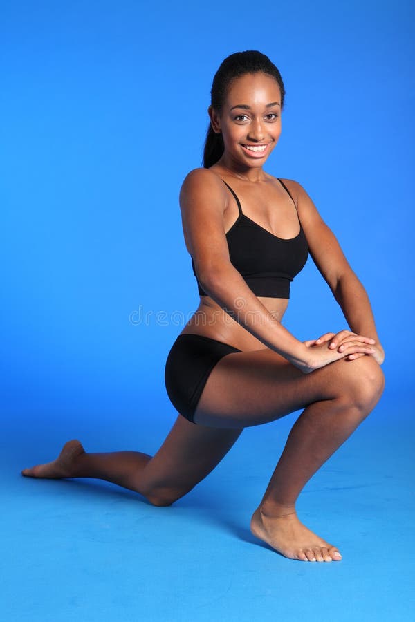 Kneeling hip flexor stretch exercise on floor by a beautiful young athletic african american fitness woman wearing black sports bra and briefs underwear. Kneeling hip flexor stretch exercise on floor by a beautiful young athletic african american fitness woman wearing black sports bra and briefs underwear.