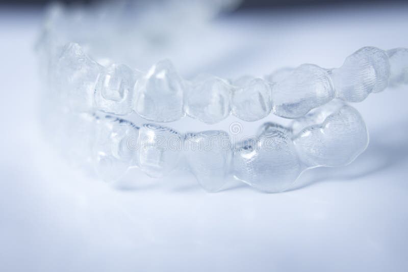 Invisible teeth aligner cosmetic orthodontic brackets used to straighten and align teeth in patient with clear plastic see through aesthetic look. Invisible teeth aligner cosmetic orthodontic brackets used to straighten and align teeth in patient with clear plastic see through aesthetic look.