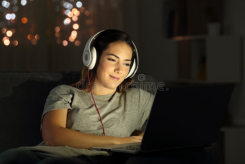 Woman watching videos online in the night sitting on a couch in the living room at home. Woman watching videos online in the night sitting on a couch in the living room at home