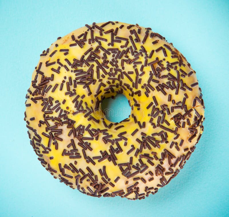 Βερνικωμένο doughnut με ζωηρόχρωμο ψεκάζει στο μπλε υπόβαθρο κρητιδογραφιών στοκ φωτογραφία