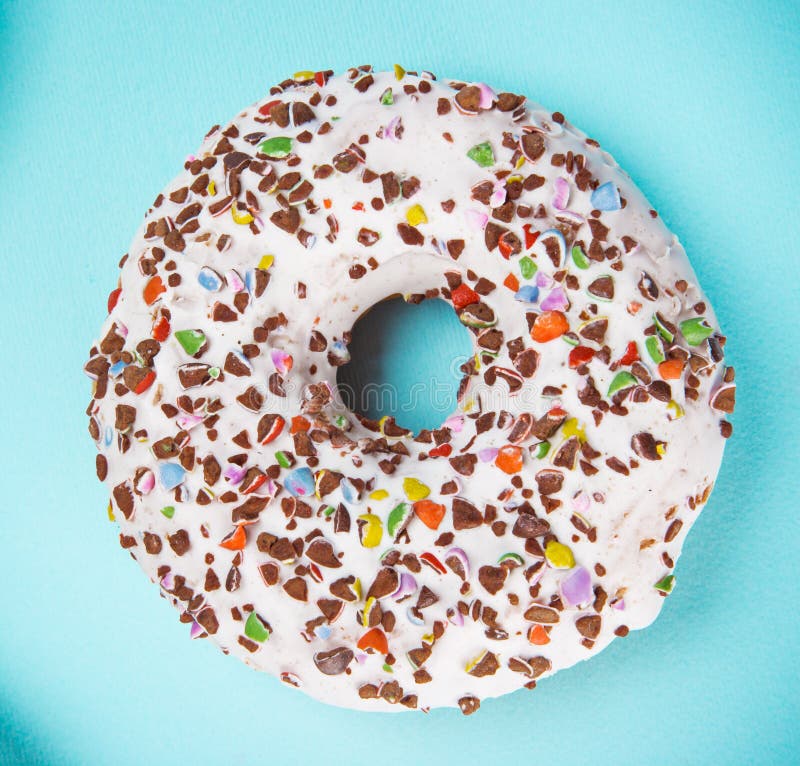 Βερνικωμένο doughnut με ζωηρόχρωμο ψεκάζει στο μπλε υπόβαθρο κρητιδογραφιών στοκ φωτογραφίες