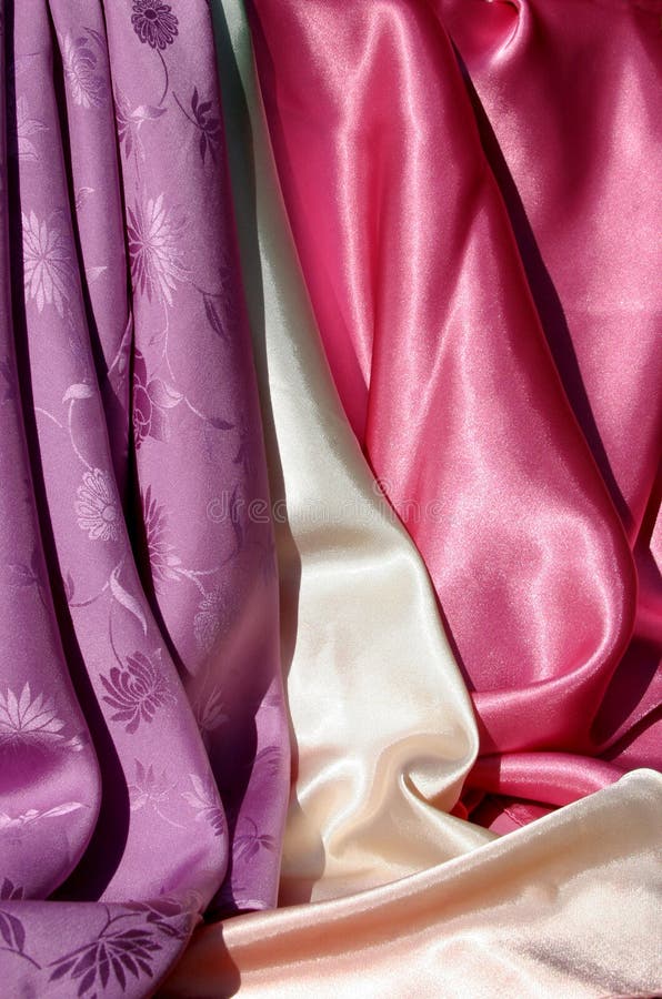 A backdrop of violet, cream and pink silky fabric. A backdrop of violet, cream and pink silky fabric.