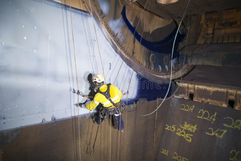 Βιομηχανικός ζωγράφος τεχνικών πρόσβασης σχοινιών αρσενικών που εργάζεται στην ένωση ύψους στα δίδυμα σχοινιά στοκ εικόνες Βιομηχανικός ζωγράφος τεχνικών πρόσβασης σχοινιών αρσενικών που εργάζεται στην ένωση ύψους στα δίδυμα σχοινιά στοκ εικόνες