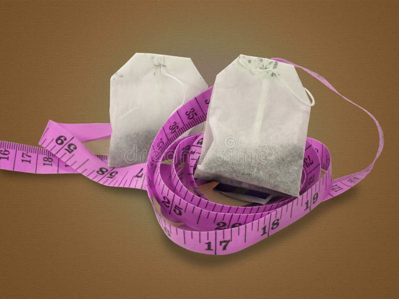 Two herbal tea bags nestled on top of a pink measuring tape isolated on a brown textured background. Two herbal tea bags nestled on top of a pink measuring tape isolated on a brown textured background