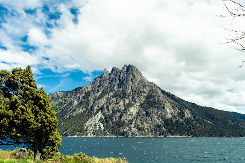 Rocky mountain on a coast with tree in the foreground. Nahuel Huapi lake, Bariloche. Rocky mountain on a coast with tree in the foreground. Nahuel Huapi lake, Bariloche