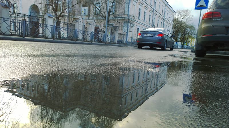 βροχερός λυπημένος παγωμένος καιρός. αυτοκίνητα σε υγρό δρόμο. αντανάκλαση του σπιτιού στη λίμνη στην άσφαλτο. οδός. πάρκινγκ αυτο στοκ φωτογραφία