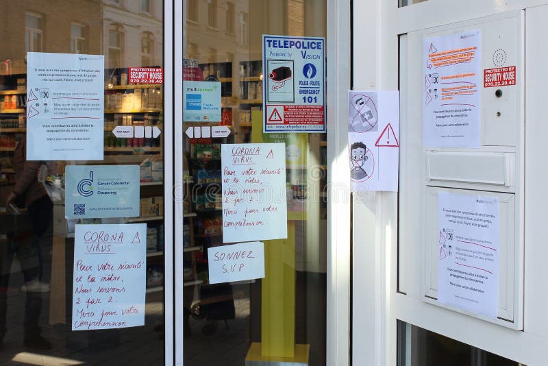 17/03/2020, Brussels, Belgium - local pharmacy entrance in Anderlecht area, handwritten warnings in French on glass doors: For your and our safety, we serve 2/2 people. Thanks for your understanding. 17/03/2020, Brussels, Belgium - local pharmacy entrance in Anderlecht area, handwritten warnings in French on glass doors: For your and our safety, we serve 2/2 people. Thanks for your understanding.