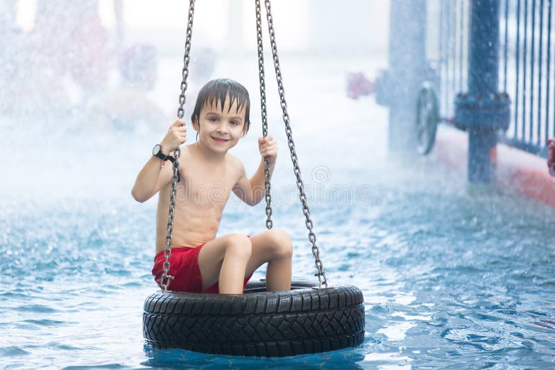 Sweet child, boy, playing in water world playground, enjoying attractions, swimming in a big swimming pool on a holiday. Sweet child, boy, playing in water world playground, enjoying attractions, swimming in a big swimming pool on a holiday