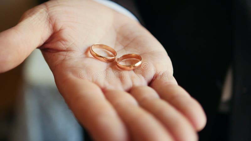 Γάμος - ο νεόνυμφος κρατά τα χρυσά γαμήλια δαχτυλίδια στην παλάμη του χεριού