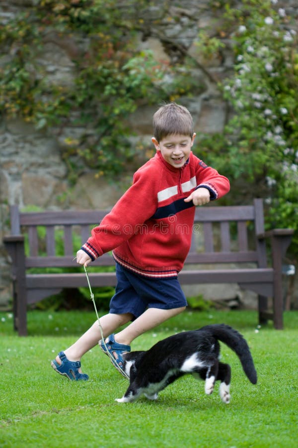 Young boy laughing and chasing his pet cat. Young boy laughing and chasing his pet cat