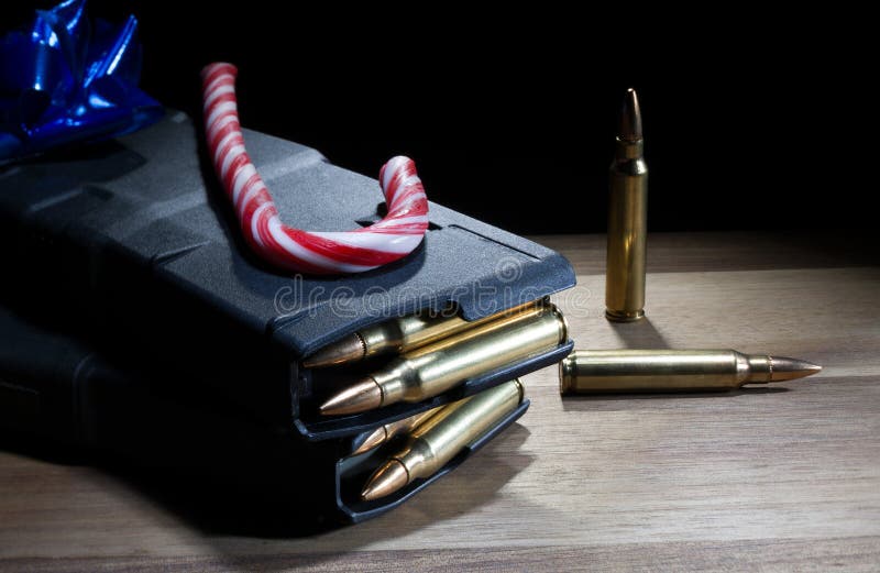 Christmas present of a pair of filled AR-15 magazines and candy cane with a blue bow on top with a black background. Christmas present of a pair of filled AR-15 magazines and candy cane with a blue bow on top with a black background