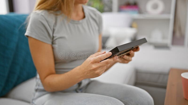 για την άνεση του σπιτιού της, οι γυναίκες κρατούν ένα πλαίσιο εικόνας ενώ ξεκουράζονται σε καναπέ στοκ εικόνα