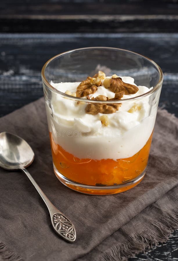 Γιαούρτι με persimmon και καρύδια σε ένα γυαλί Επιδόρπιο σε έναν ξύλινο πίνακα με ένα κουτάλι και μια πετσέτα στοκ φωτογραφία με δικαίωμα ελεύθερης χρήσης Γιαούρτι με persimmon και καρύδια σε ένα γυαλί Επιδόρπιο σε έναν ξύλινο πίνακα με ένα κουτάλι και μια πετσέτα στοκ φωτογραφία με δικαίωμα ελεύθερης χρήσης