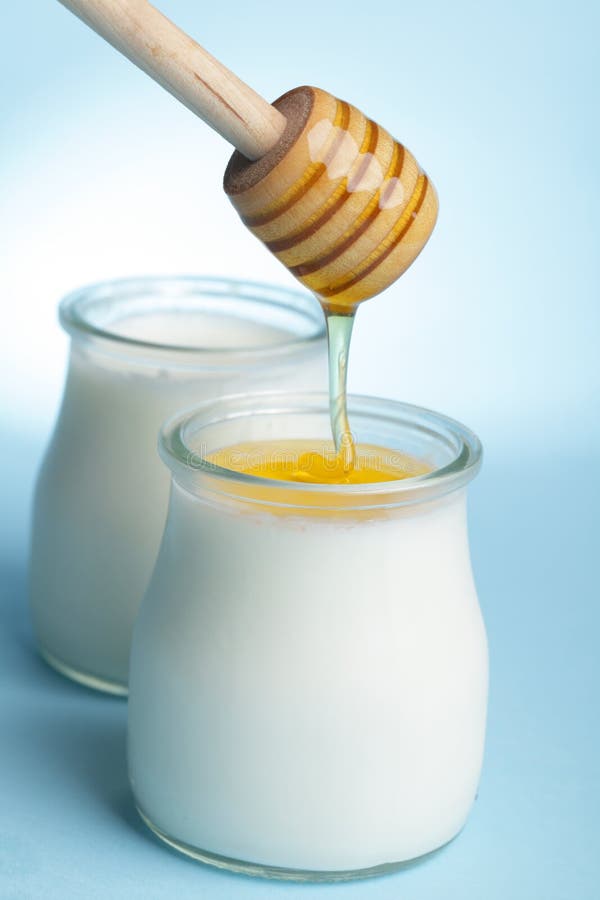 Yogurt and pouring honey against blue background. Yogurt and pouring honey against blue background