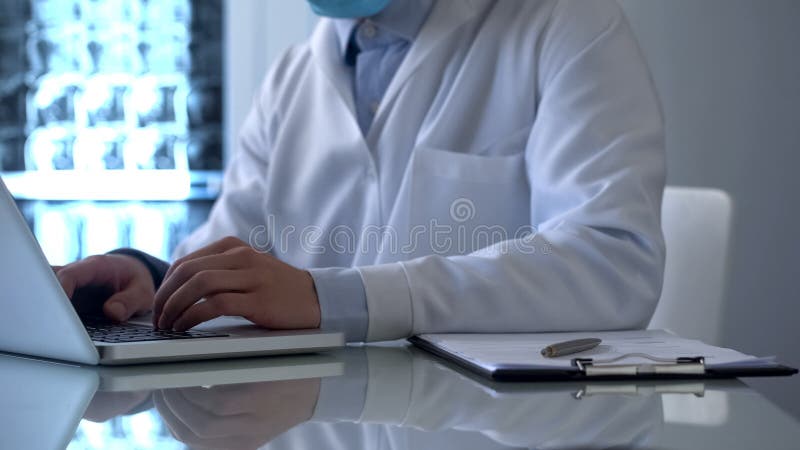 Γιατρός Roengenologist που εργάζεται στο lap-top, γεμίζοντας στοιχεία στις σε απευθείας σύνδεση ιατρικές αναφορές στοκ εικόνα Γιατρός Roengenologist που εργάζεται στο lap-top, γεμίζοντας στοιχεία στις σε απευθείας σύνδεση ιατρικές αναφορές στοκ εικόνα