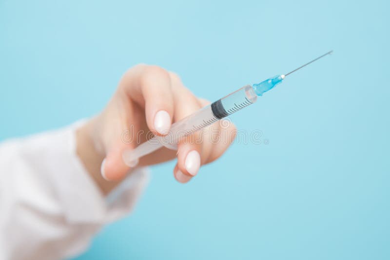 Γιατρός λουτρών ομορφιάς που κρατά σύριγγα σε μπλε φόντο Γυναικείο χέρι με μανικιούρ στοκ εικόνα Γιατρός λουτρών ομορφιάς που κρατά σύριγγα σε μπλε φόντο Γυναικείο χέρι με μανικιούρ στοκ εικόνα