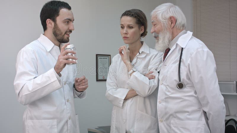 Γιατρός που κρατά ένα μπουκάλι ιατρικής και που προάγει στους συναδέλφους του