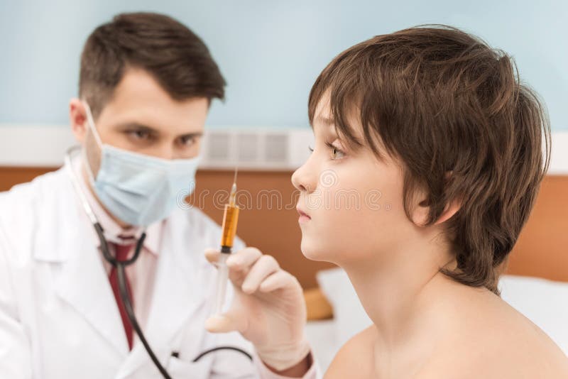 Γιατρός στην ιατρική σύριγγα εκμετάλλευσης μασκών για την έγχυση στον ασθενή αγοριών στοκ φωτογραφίες με δικαίωμα ελεύθερης χρήσης