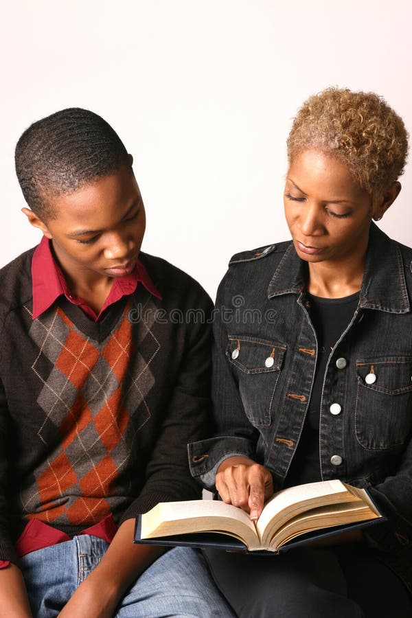 Mother and teenage son review school assignment in open book. Mother and teenage son review school assignment in open book