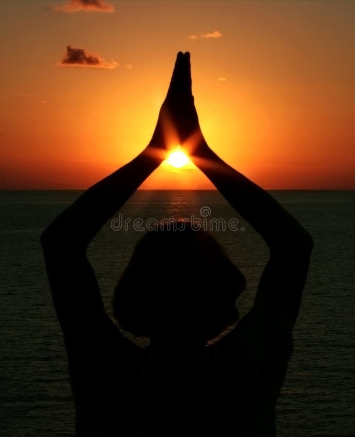 A human being doing a zen meditation in front of the sun and sea. A human being doing a zen meditation in front of the sun and sea.