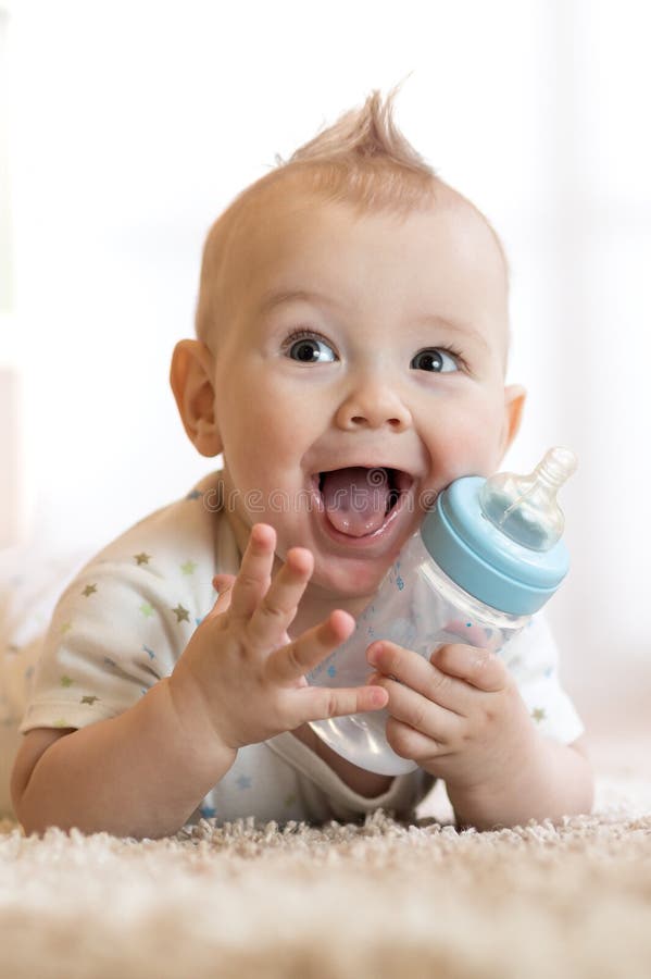 Sweet baby boy holding bottle with water and smiling. Sweet baby boy holding bottle with water and smiling