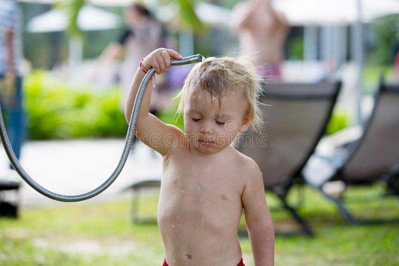 Sweet toddler boy, taking a shower on outdoor showers on the beach, splashing water. Sweet toddler boy, taking a shower on outdoor showers on the beach, splashing water