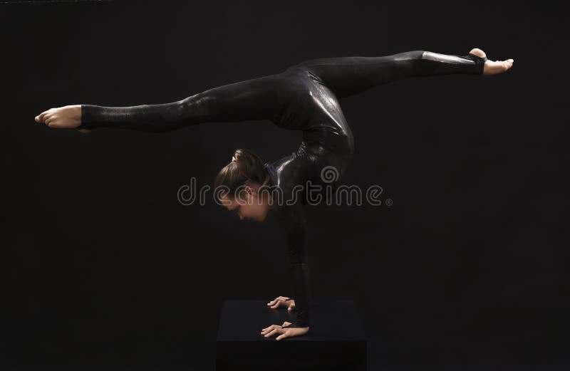 Γοητευτικός gymnast κοριτσιών, σε ένα μαύρο κοστούμι, συμμετείχε στο acrobatics λαμβάνοντας υπόψη τον ενάντιο στοκ εικόνες Γοητευτικός gymnast κοριτσιών, σε ένα μαύρο κοστούμι, συμμετείχε στο acrobatics λαμβάνοντας υπόψη τον ενάντιο στοκ εικόνες