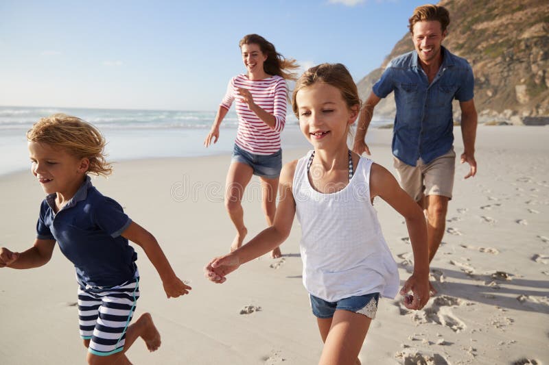 Γονείς που τρέχουν κατά μήκος της παραλίας με τα παιδιά στις θερινές διακοπές