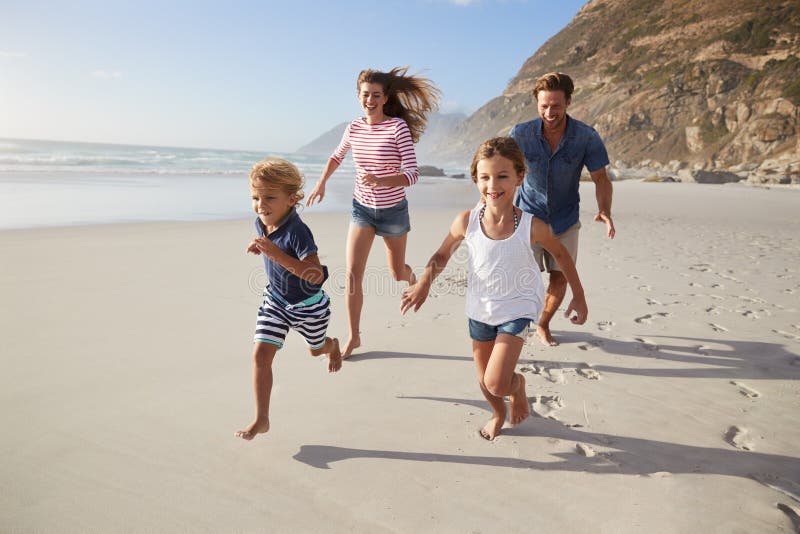 Γονείς που τρέχουν κατά μήκος της παραλίας με τα παιδιά στις θερινές διακοπές