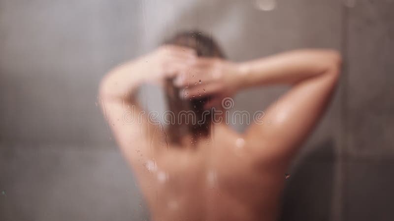 γυμνή γυναίκα που πλένει καστανά μαλλιά με σαμπουάν και σώμα με τζελ στο ντους. απόθεμα βίντεο