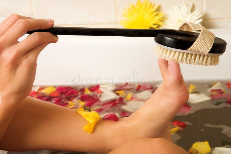 Woman in a bath scrubbing her feet with a brush. Woman in a bath scrubbing her feet with a brush