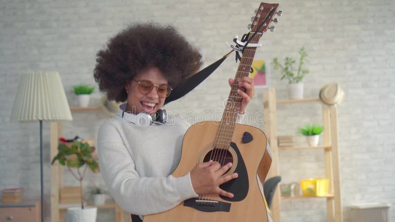 Γυναίκα αφροαμερικάνων πορτρέτου με ένα εκφραστικό παιχνίδι afro hairstyle στην κιθάρα