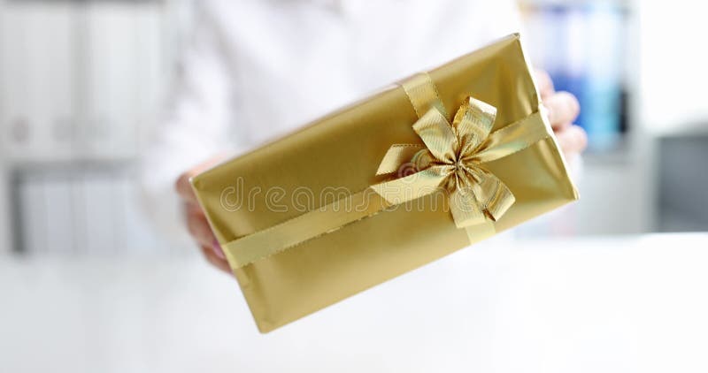 γυναίκα δίνει δώρο σε ένα χρυσό κουτί με το τόξο κλειστό