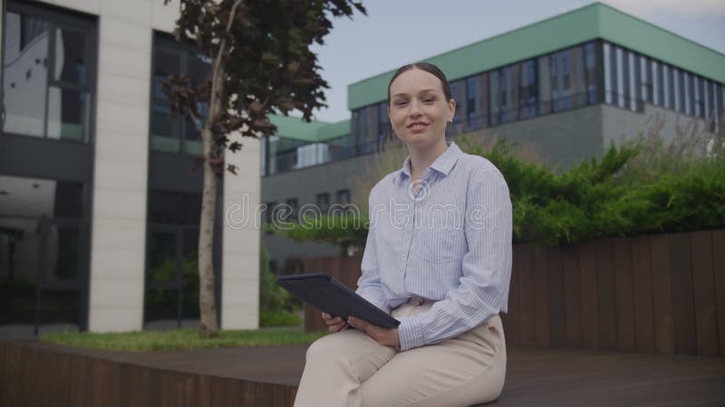 Γυναίκα Διαβάζει Tablet Κοιτάζει Επάνω Στην Κάμερα Και Χαμογελά Σε Εξωτερικό Χώρο Με Επιχειρηματικά Κέντρα απόθεμα βίντεο