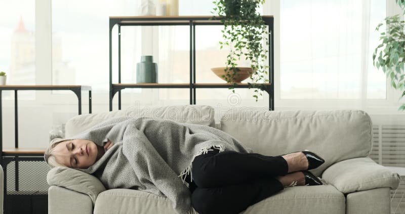 γυναίκα επιχειρηματίας κοιμάται στον καναπέ τυλιγμένη σε κουβέρτα