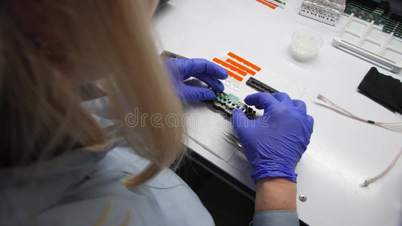 γυναίκα εργάτης εγκαθιστά λεπτομέρειες συναρμολόγησης τσιπ σε λευκό τραπέζι φιλμ μικρού μήκους