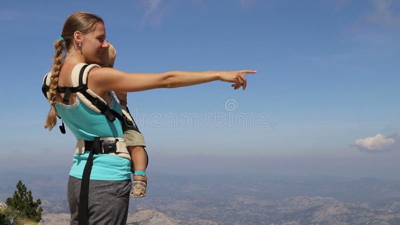 Γυναίκα κρατά το παιδί στα χέρια και δείχνει στα βουνά, δίπλα απόθεμα βίντεο
