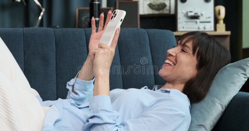 γυναίκα ξαπλωμένη στον καναπέ χρησιμοποιώντας το τηλέφωνό της