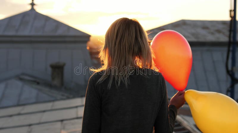 Γυναίκα που αισθάνεται το ευτυχές περπάτημα με το μπαλόνι στη στέγη υποστηρίξτε την όψη