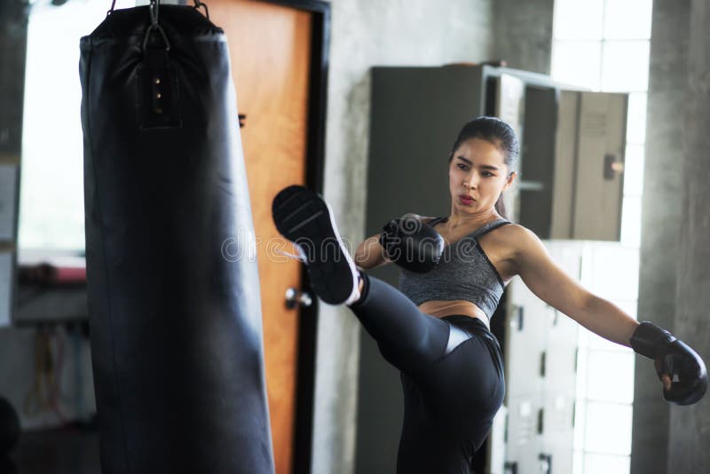 Asian Female boxer kicking huge punching bag at fitness gym. Athletic sexy girl training Thai boxing punch and kick for bodybuilding and healthy lifestyle concept. Happy woman workout in sport club, action, active, arena, arts, athlete, background, beautiful, black, blow, cuff, exercise, fight, fighter, gloves, hitting, kickboxing, martial, muscular, people, portrait, power, ring, sportswear, strength, strong, sweat, tired, trainer, young. Asian Female boxer kicking huge punching bag at fitness gym. Athletic sexy girl training Thai boxing punch and kick for bodybuilding and healthy lifestyle concept. Happy woman workout in sport club, action, active, arena, arts, athlete, background, beautiful, black, blow, cuff, exercise, fight, fighter, gloves, hitting, kickboxing, martial, muscular, people, portrait, power, ring, sportswear, strength, strong, sweat, tired, trainer, young