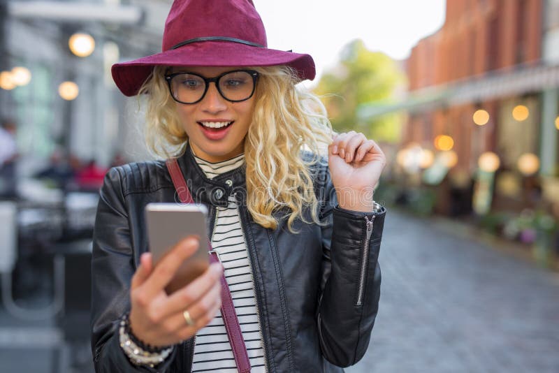 Γυναίκα που εξετάζει το smartphone της στην ευχάριστη έκπληξη στοκ εικόνα Γυναίκα που εξετάζει το smartphone της στην ευχάριστη έκπληξη στοκ εικόνα